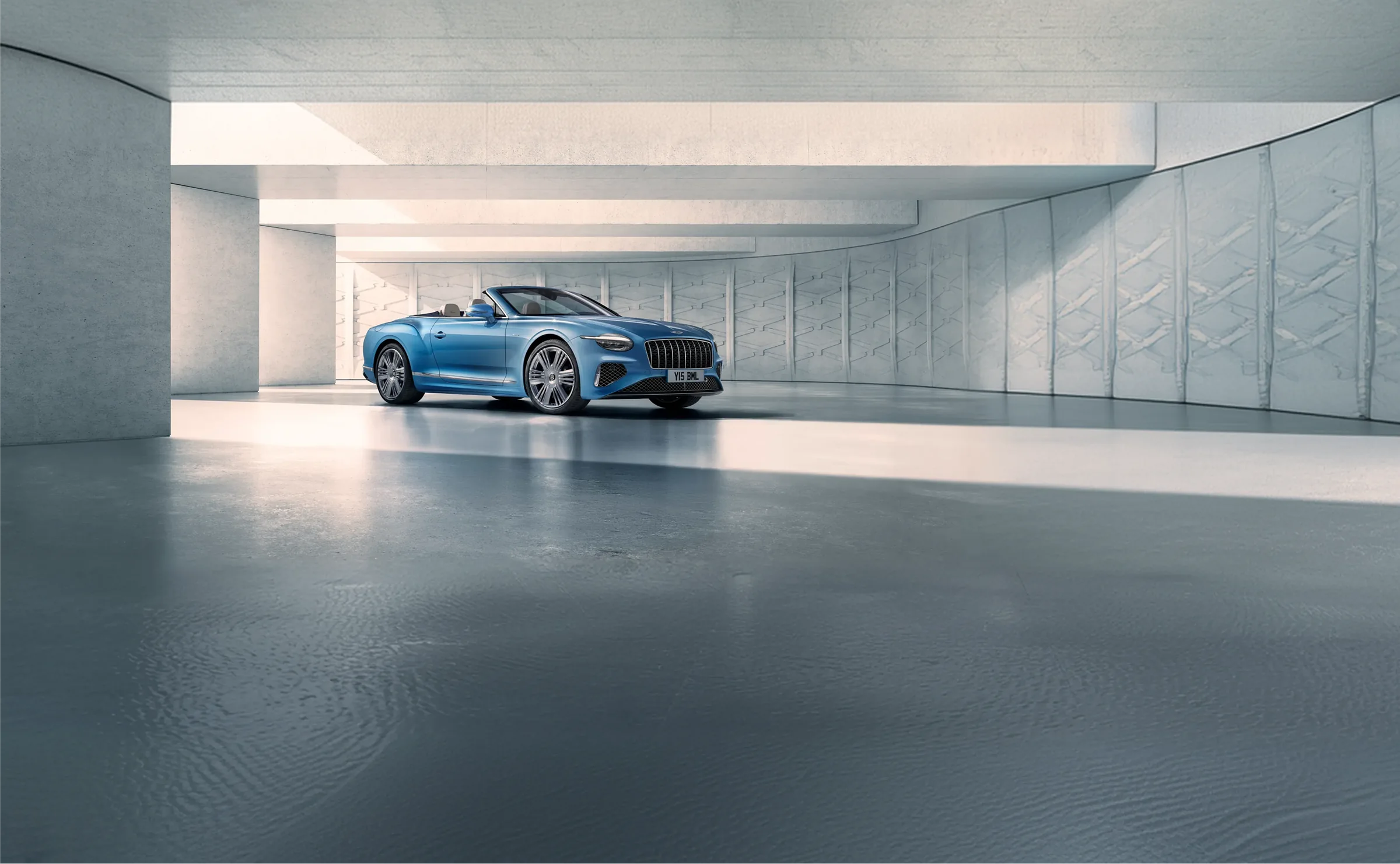 A Bentley Continental GTC in blue with the roof lowered, standing alone in a pale concrete hall.